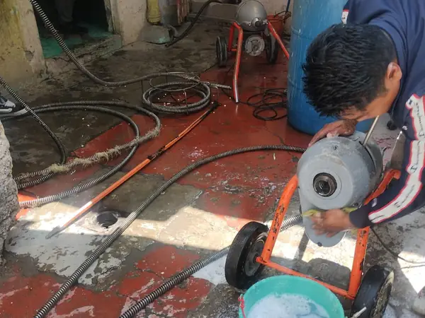 Plomero de Plomería Torres destapando una cañería con máquina de sonda eléctrica de tambor
