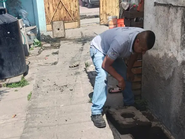 Plomero revisando un registro de drenaje en un pasillo junto al tinaco