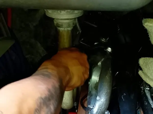 Plomero ajustando la conexión del desagüe debajo de una tarja