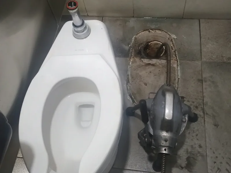 WC comercial retirado y máquina de sonda lista para destapar el desagüe